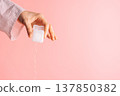 Hand pulling dental floss from a white container on pink background, oral care routine with copy space 137850382