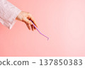 Hand holding a single tuft toothbrush on pink background, minimal oral care concept with copy space 137850383