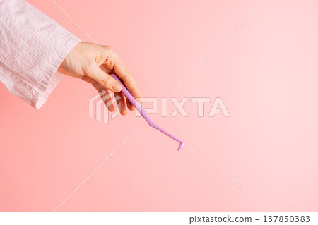 Hand holding a single tuft toothbrush on pink background, minimal oral care concept with copy space Hand holding a single tuft toothbrush on pink background, minimal oral care concept with copy space 137850383