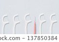 Dental floss picks lined up with an interdental brush, oral hygiene tools comparison on light blue background 137850384