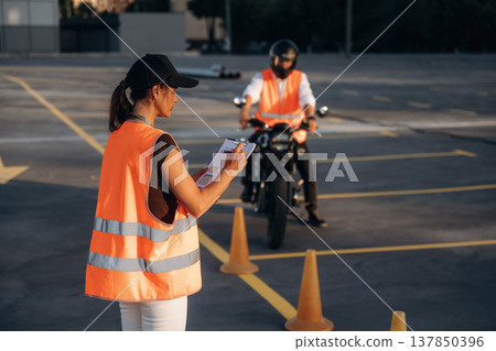 Writing the results into notepad. Motorcycle driving license exam. Man and woman are in uniforms 137850396