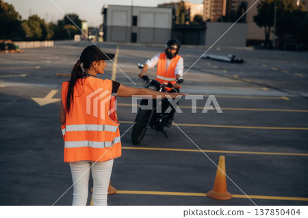 Showing where to go. Motorcycle driving license exam. Man and woman are in uniforms 137850404