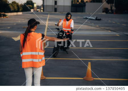 Showing where to go. Motorcycle driving license exam. Man and woman are in uniforms 137850405