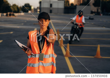 Stop hand gesture. Motorcycle driving license exam. Man and woman are in uniforms Stop hand gesture. Motorcycle driving license exam. Man and woman are in uniforms 137850408