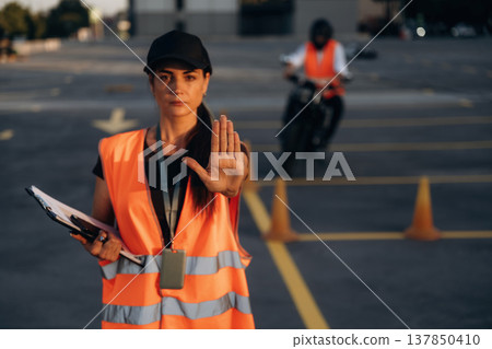 Stop hand gesture. Motorcycle driving license exam. Man and woman are in uniforms 137850410