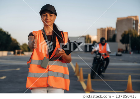 Giving hand to shake, welcome. Motorcycle driving license exam. Man and woman are in uniforms Giving hand to shake, welcome. Motorcycle driving license exam. Man and woman are in uniforms 137850413