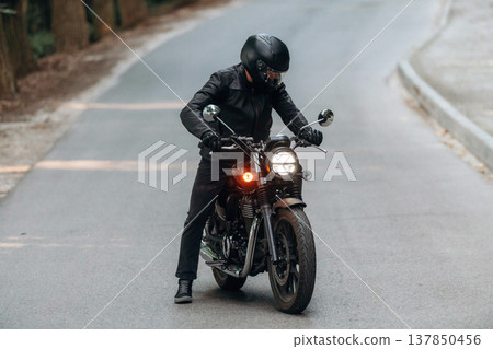 In leather clothes. Man is on motorcycle is on the road In leather clothes. Man is on motorcycle is on the road 137850456