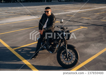 Leaning on the bike. Man is outdoors with his motorcycle Leaning on the bike. Man is outdoors with his motorcycle 137850480