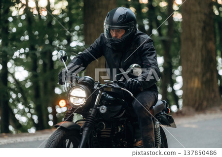 Protective helmet on head, safety first. Man in leather clothes on motorcycle is on the road Protective helmet on head, safety first. Man in leather clothes on motorcycle is on the road 137850486
