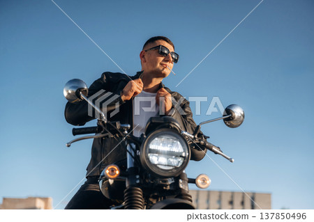 In cool sunglasses. Man is outdoors with his motorcycle In cool sunglasses. Man is outdoors with his motorcycle 137850496