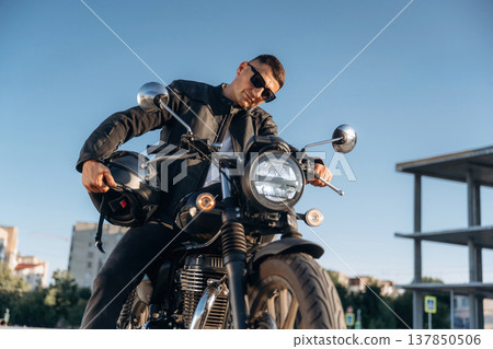 Bright sunlight, parked. Man is outdoors with his motorcycle 137850506