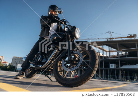 Unrecognizable in the protective hat. Man is outdoors with his motorcycle Unrecognizable in the protective hat. Man is outdoors with his motorcycle 137850508