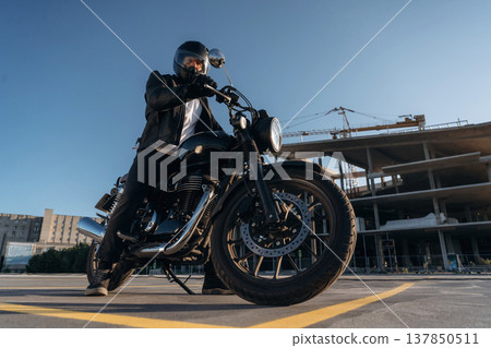 Unrecognizable in the protective hat. Man is outdoors with his motorcycle Unrecognizable in the protective hat. Man is outdoors with his motorcycle 137850511