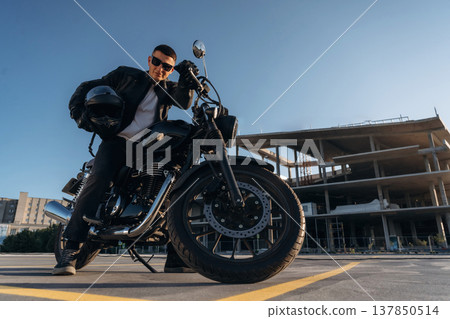 Bright sunlight, parked. Man is outdoors with his motorcycle Bright sunlight, parked. Man is outdoors with his motorcycle 137850514