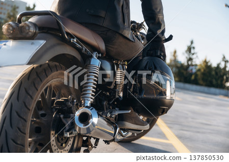 Holding protective helmet in hand. Close up detailed view of man with motorcycle Holding protective helmet in hand. Close up detailed view of man with motorcycle 137850530