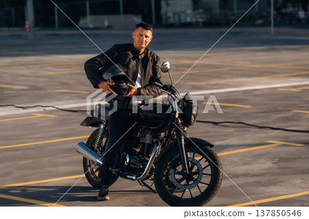 Man is outdoors with his motorcycle Man is outdoors with his motorcycle 137850546