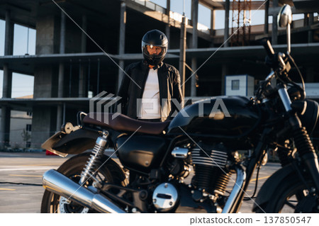 Man is outdoors with his motorcycle Man is outdoors with his motorcycle 137850547