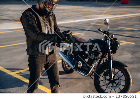 Unrecognizable in the protective hat. Man is outdoors with his motorcycle 137850551