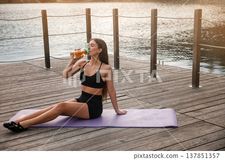 Attractive Woman Drinking Water After Workout At Lake. Fitness Hydration And Recovery Concept Attractive Woman Drinking Water After Workout At Lake. Fitness Hydration And Recovery Concept 137851357