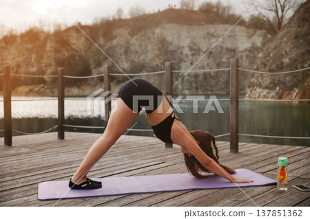 Young Woman Practicing Downward Dog Yoga Pose Outdoors At Lake. Flexibility And Stretching Concept 137851362