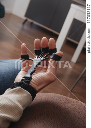 a man trains his fingers with a grip trainer a man trains his fingers with a grip trainer 137852117