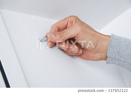 a man inserts a wall plug into a drilled hole a man inserts a wall plug into a drilled hole 137852122