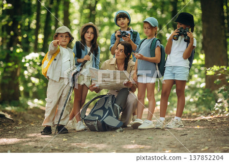 Gathered together. Woman is doing tour for group of kids in the forest Gathered together. Woman is doing tour for group of kids in the forest 137852204