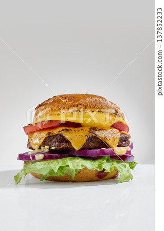 Juicy cheeseburger with melted cheese and grilled patty close up on clean white background. Juicy cheeseburger with melted cheese and grilled patty close up on clean white background. 137852233