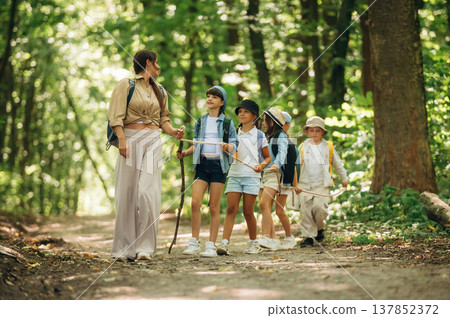 Leading the way. Woman is doing tour for group of kids in the forest Leading the way. Woman is doing tour for group of kids in the forest 137852372