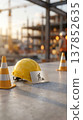 Construction site safety equipment including hard hat and traffic cones with a work in progress sign 137852635