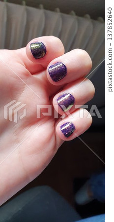 Phone photo of a home manicure with purple and green duochrome nail polish. Casual beauty scene showing self care, grooming, and everyday lifestyle. Phone photo of a home manicure with purple and green duochrome nail polish. Casual beauty scene showing self care, grooming, and everyday lifestyle. 137852640