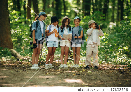 Camera and paper map in hands. Group of children in the forest on a hike Camera and paper map in hands. Group of children in the forest on a hike 137852758