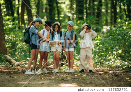 Camera and paper map in hands. Group of children in the forest on a hike Camera and paper map in hands. Group of children in the forest on a hike 137852761