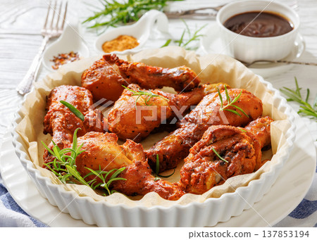 Roasted chicken drumsticks on paper in baking dish 137853194