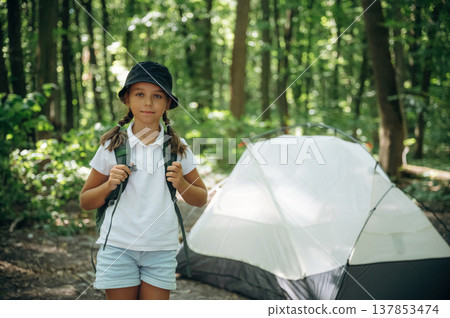 Green backpack on the back. Young girl hiker is in the forest Green backpack on the back. Young girl hiker is in the forest 137853474