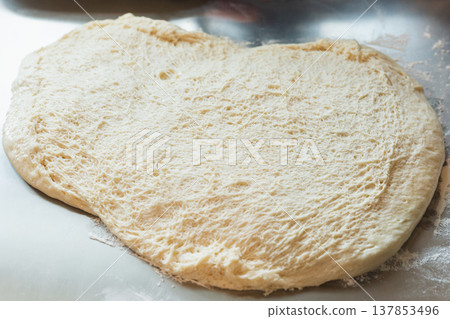 Freshly proofed bread dough with airy texture spread on a floured surface, ready for baking. Freshly proofed bread dough with airy texture spread on a floured surface, ready for baking. 137853496
