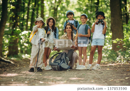 Gathered together. Woman is doing tour for group of kids in the forest Gathered together. Woman is doing tour for group of kids in the forest 137853590