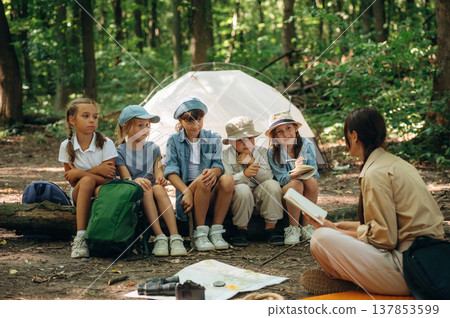 Laughing at story, smiling. Woman is doing tour for group of kids in the forest Laughing at story, smiling. Woman is doing tour for group of kids in the forest 137853599