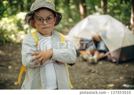 Arms crossed, boy is standing. Happy kids are with tent in the forest 137853810