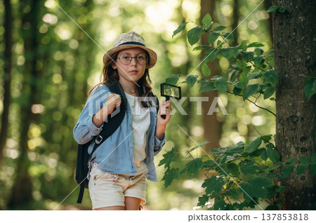 Looking straight into the camera. Young girl hiker is in the forest 137853818