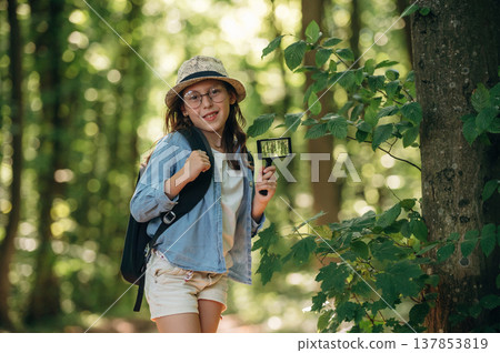 Looking straight into the camera. Young girl hiker is in the forest 137853819