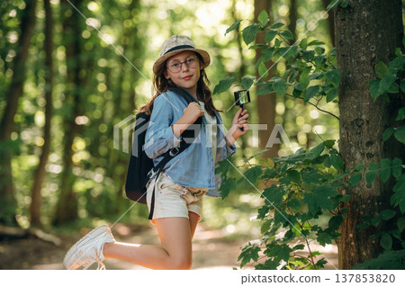Looking straight into the camera. Young girl hiker is in the forest 137853820