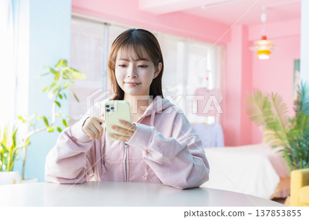 一位年輕女子在房間裡看著她的智慧型手機 137853855