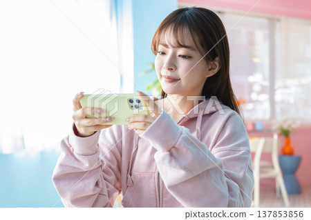 一位年輕女子在房間裡看著她的智慧型手機 137853856