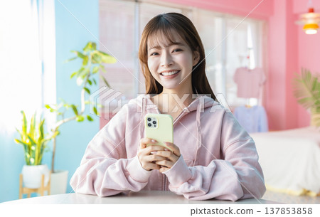 看智能手機的婦女在屋子裡 看智能手機的婦女在屋子裡 137853858