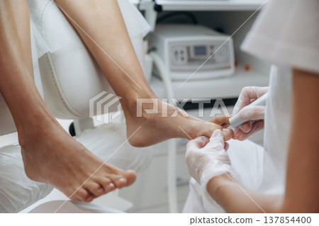 Cleaning the nail. Podiatrist with client in clinic Cleaning the nail. Podiatrist with client in clinic 137854400