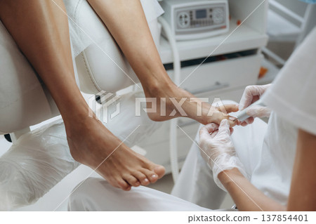 Cleaning the nail. Podiatrist with client in clinic Cleaning the nail. Podiatrist with client in clinic 137854401