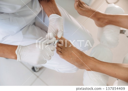 Nails cutting. Podiatrist with client in clinic 137854409