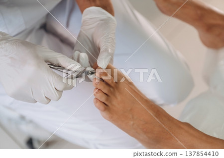 Nails cutting. Podiatrist with client in clinic 137854410