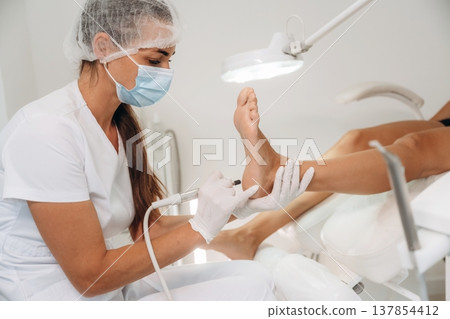 Professional care, work in progress. Podiatrist with client in clinic 137854412